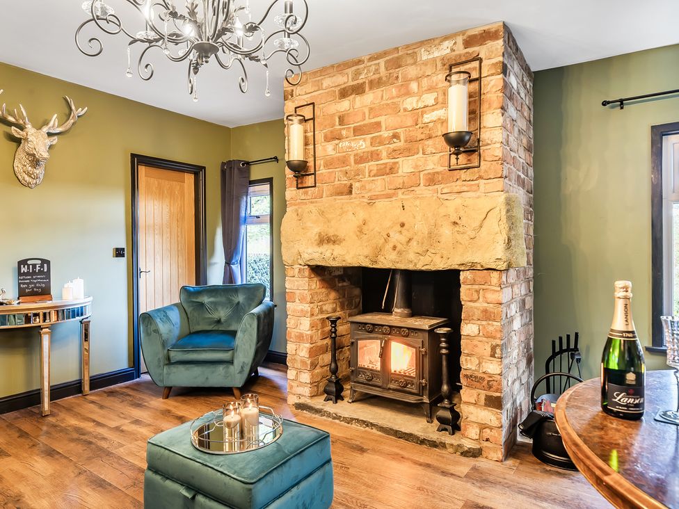 A living room with a fireplace and armchair at The Stables in Poulton-le-Fylde