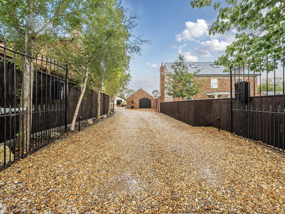 A gravel driveway with iron gates and brick houses at The Stables in Poulton-le-Fylde