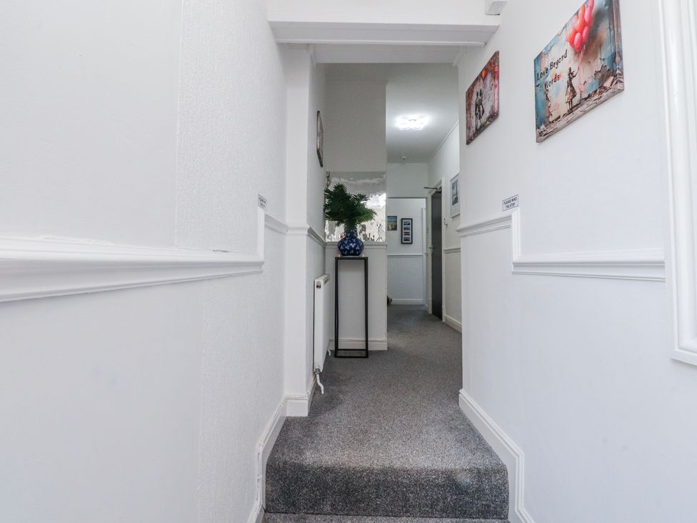 A hallway with a plant on a stand and pictures on the wall at Bliss in Lytham St. Annes