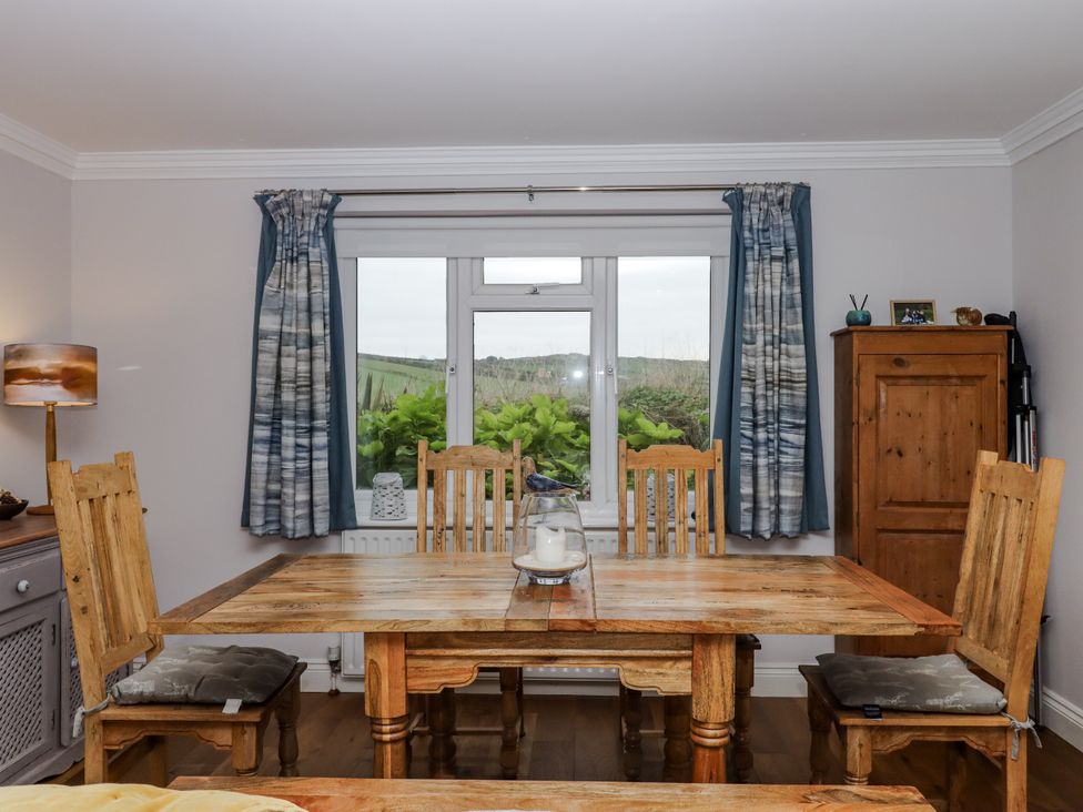 A dining room with a wooden table and window at 8 Thurlestone Rock in Kingsbridge