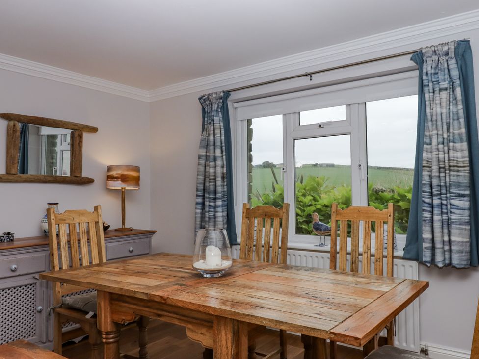 A dining area with a wooden table and chairs at 8 Thurlestone Rock in Kingsbridge