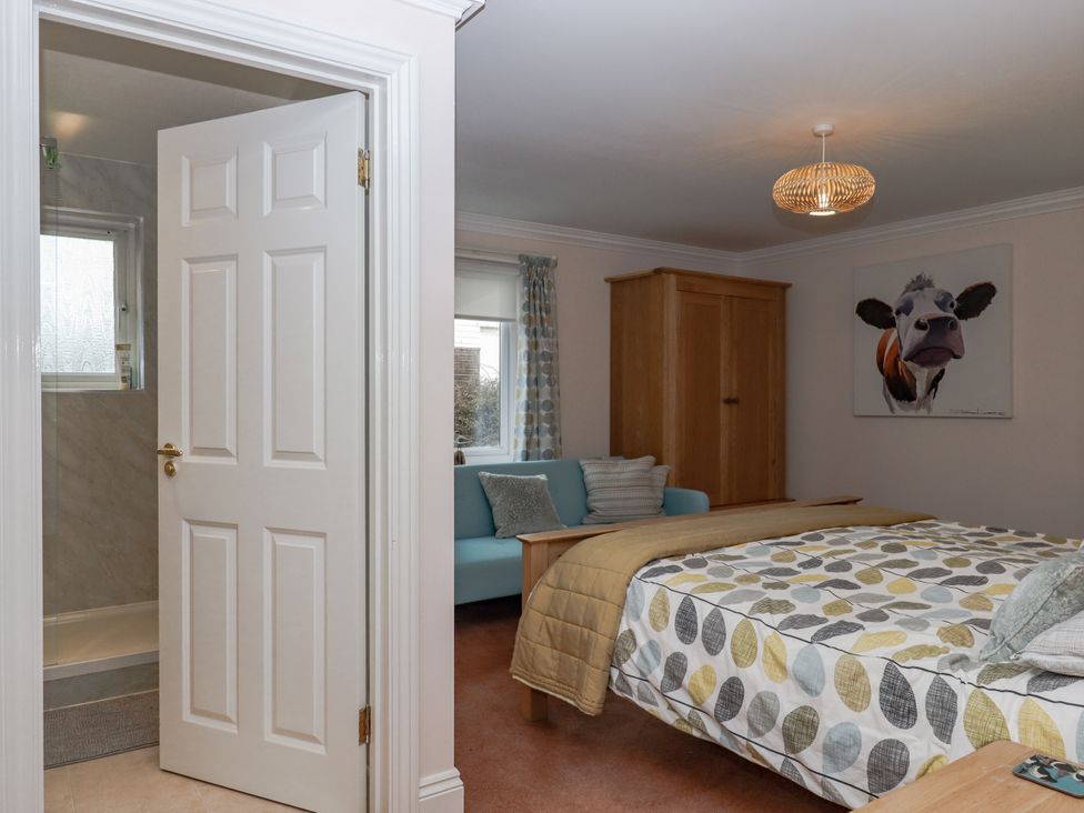 A bedroom with a bed, wardrobe, and couch at 8 Thurlestone Rock in Kingsbridge