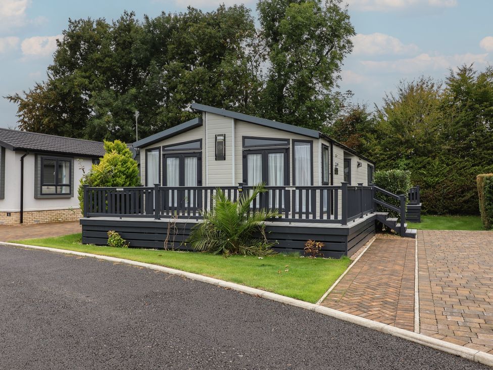A mobile home with a deck and palm tree at Whistler in Wimborne