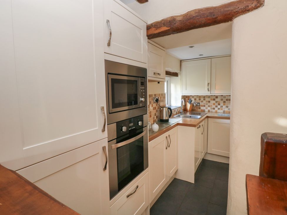 A kitchen with cabinets, microwave, oven, sink and kettle at Carthouse Cottage in Clarbeston Road