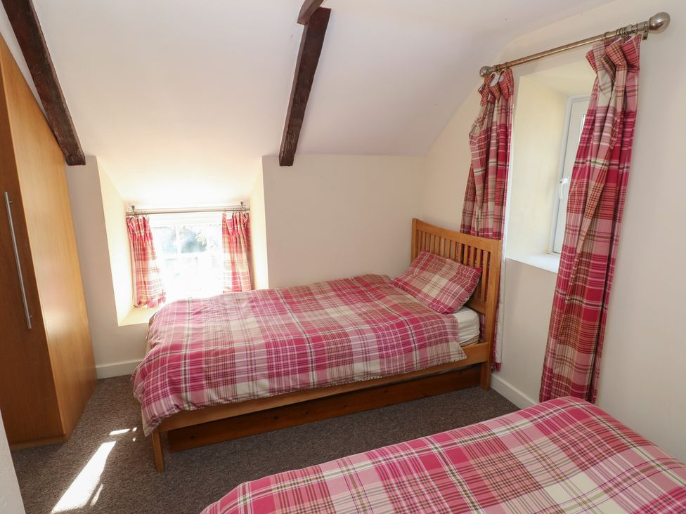A bedroom with two beds and a wardrobe at Carthouse Cottage in Clarbeston Road