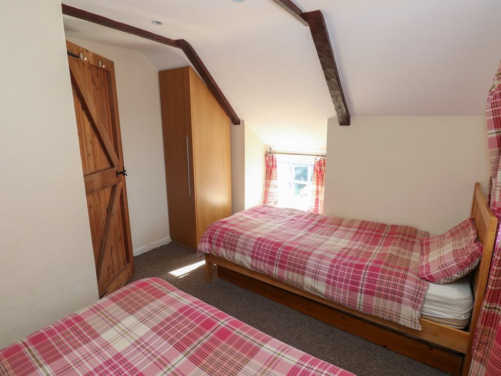 A bedroom with two beds and a wardrobe at Carthouse Cottage in Clarbeston Road