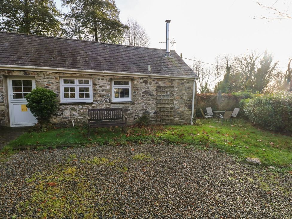 A stone cottage with bench and chairs in the garden at Knap Cottage, Clarbeston Road