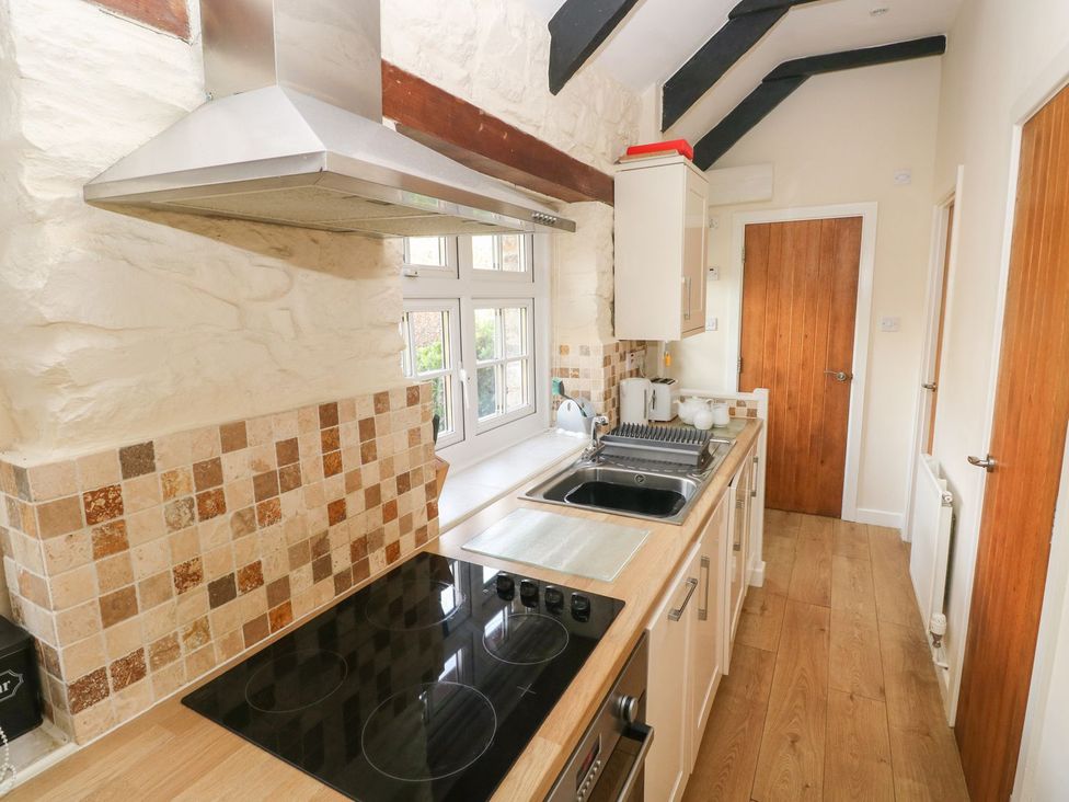 A kitchen with a stove, sink and windows at Knap Cottage in Clarbeston Road