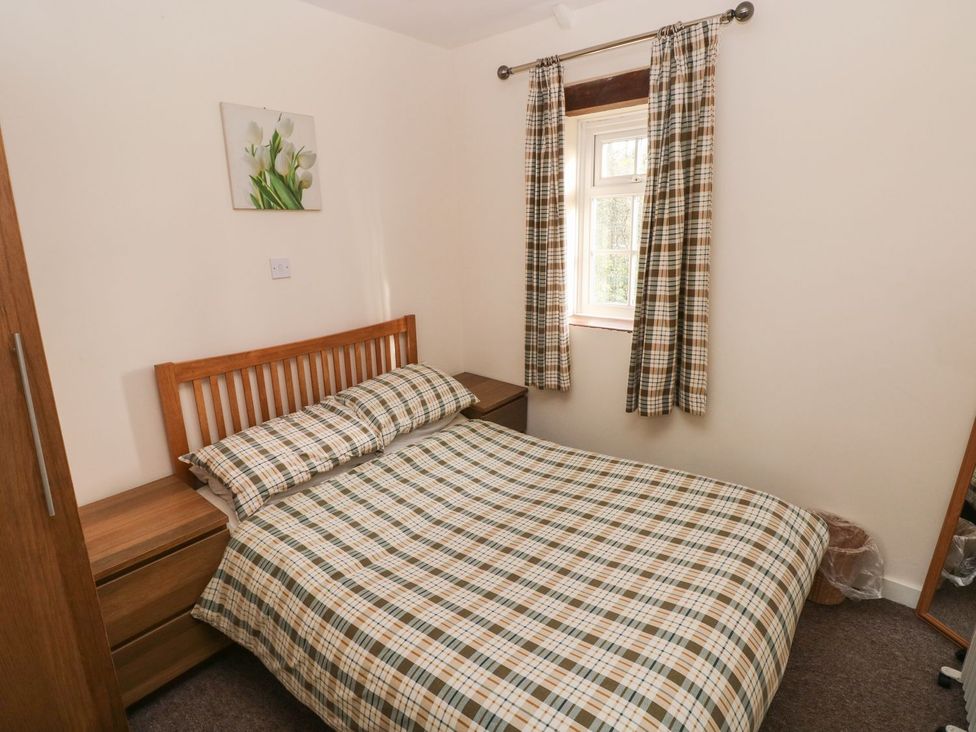 A bedroom with a bed and bedside table at Knap Cottage in Clarbeston Road