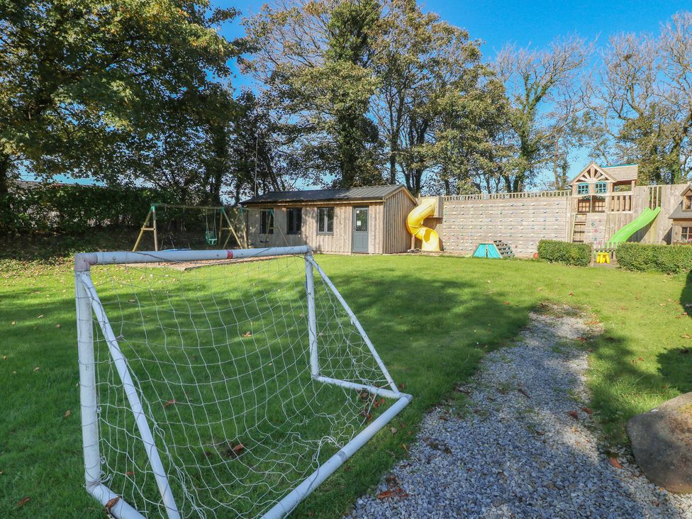 A garden with a goalpost, swings, a slide, and a playhouse at Knap Cottage Clarbeston Road
