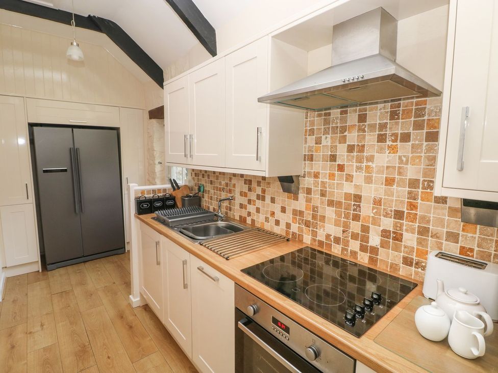 A kitchen with refrigerator, stove, and sink at Corner Cottage in Clarbeston Road