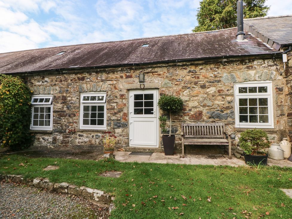 An exterior view of a stone cottage with a bench and plants at Stable Cottage in Clarbeston Road