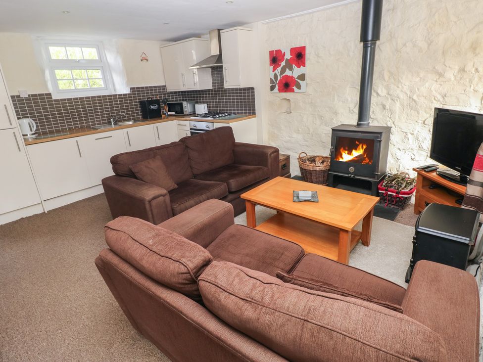 A living room with a wood stove and kitchenette at Stable Cottage in Clarbeston Road