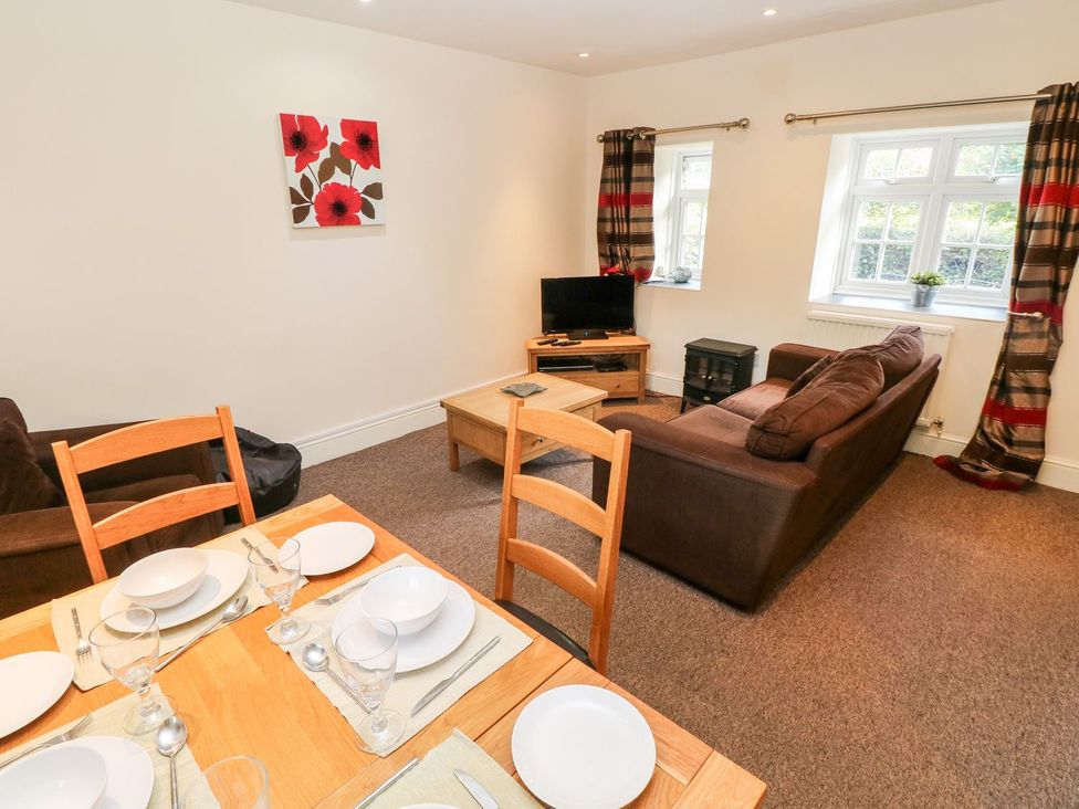 A living room with a sofa and a dining table at Swallows Cottage in Clarbeston Road