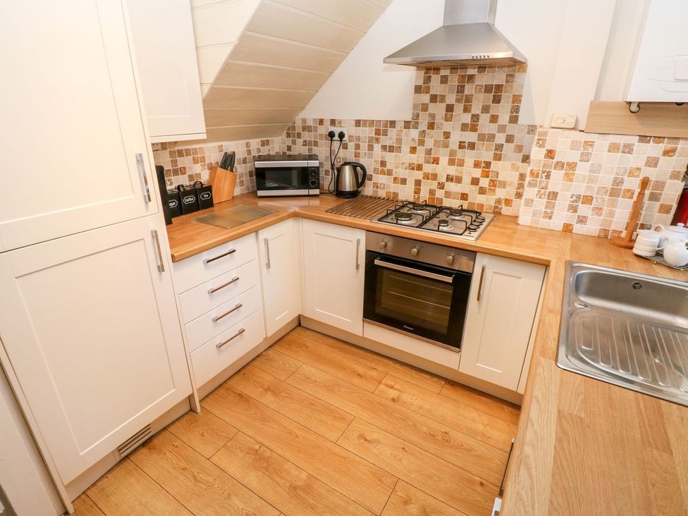 A kitchen with an oven, stove, microwave, and sink at Swallows Cottage in Clarbeston Road