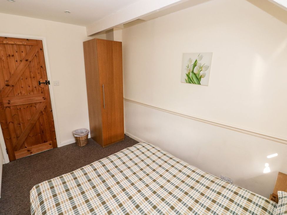 A bedroom with a bed and wardrobe at Swallows Cottage in Clarbeston Road