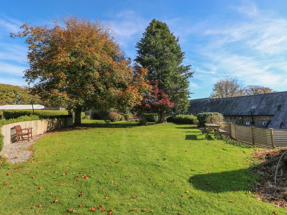 A garden with trees and benches at Swallows Cottage in Clarbeston Road