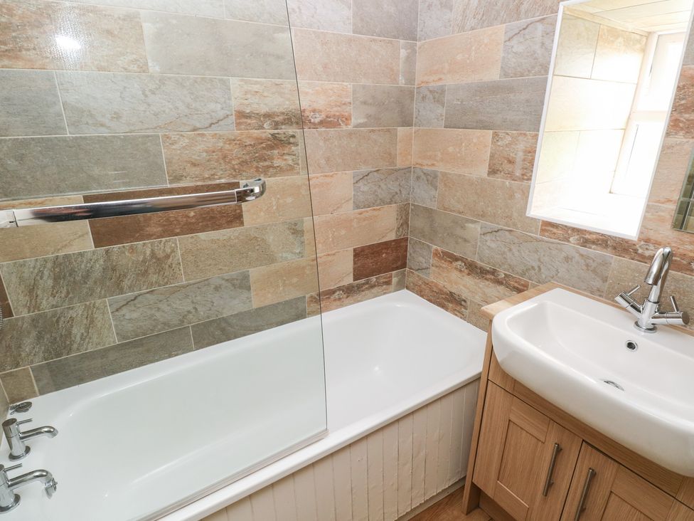 A bathroom with a bathtub and wash basin at Shippen Cottage Clarbeston Road