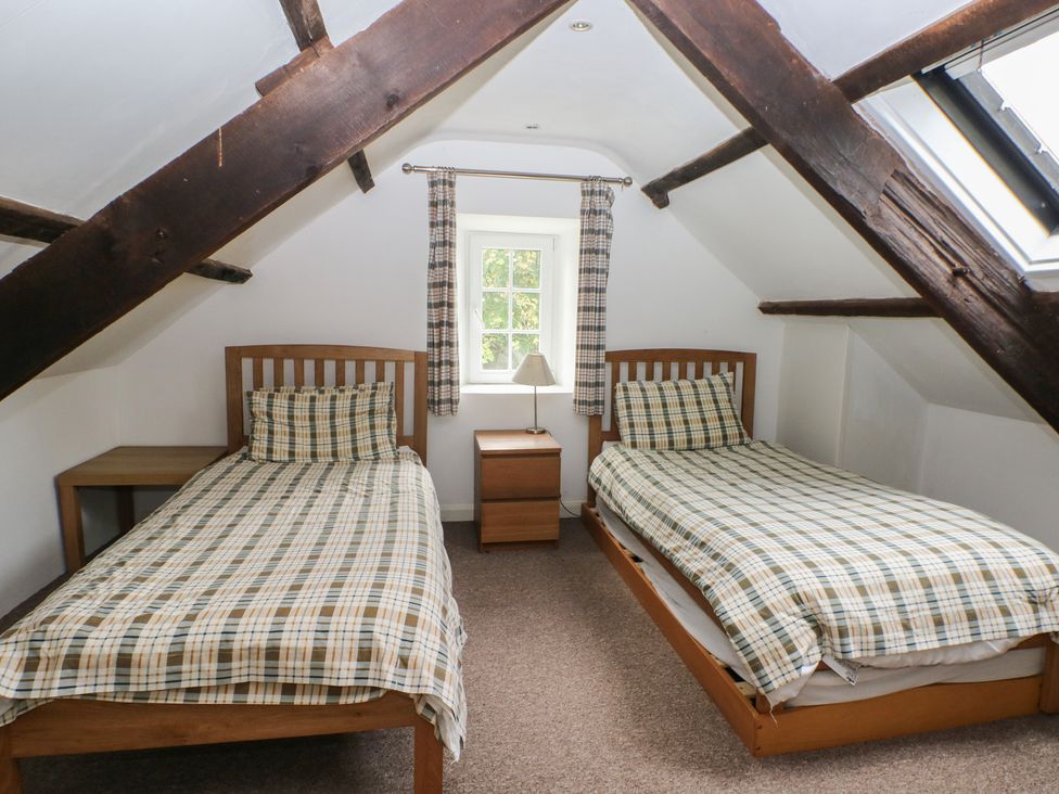 A bedroom with two beds and a nightstand at Shippen Cottage in Clarbeston Road