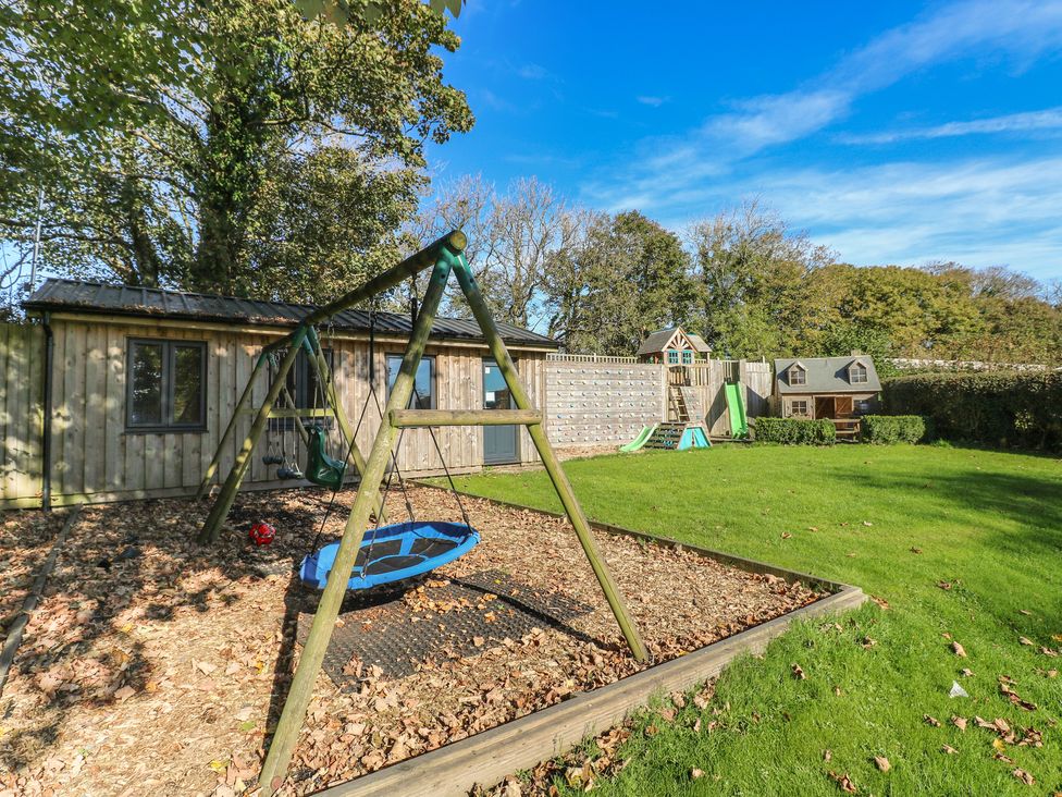 A garden with play equipment and a wooden playhouse at Shippen Cottage Clarbeston Road