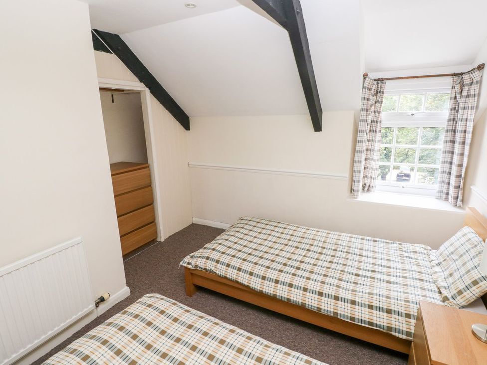 A bedroom with two beds and a dressing table at Lake Cottage in Clarbeston Road