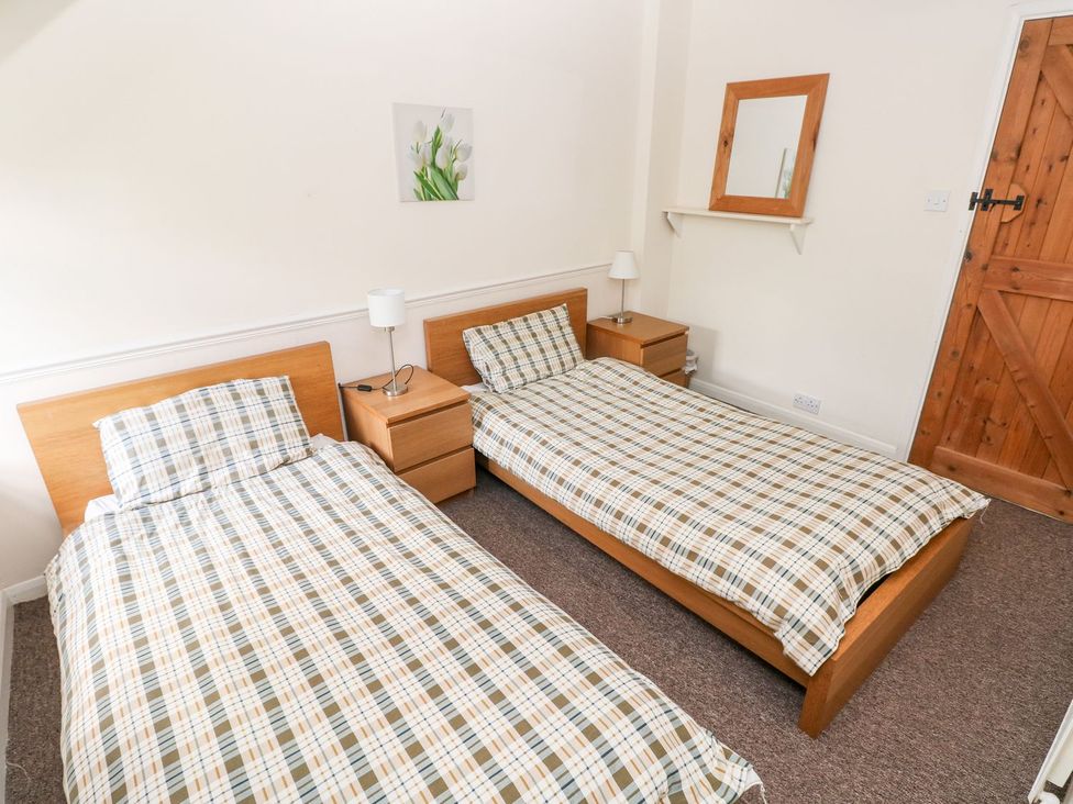 A bedroom with two single beds and a mirror at Lake Cottage in Clarbeston Road