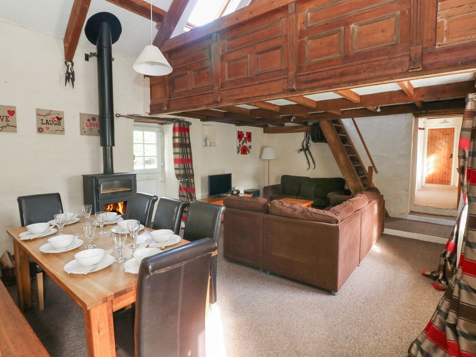 A living room with a fireplace and dining table at Granary Cottage in Clarbeston Road