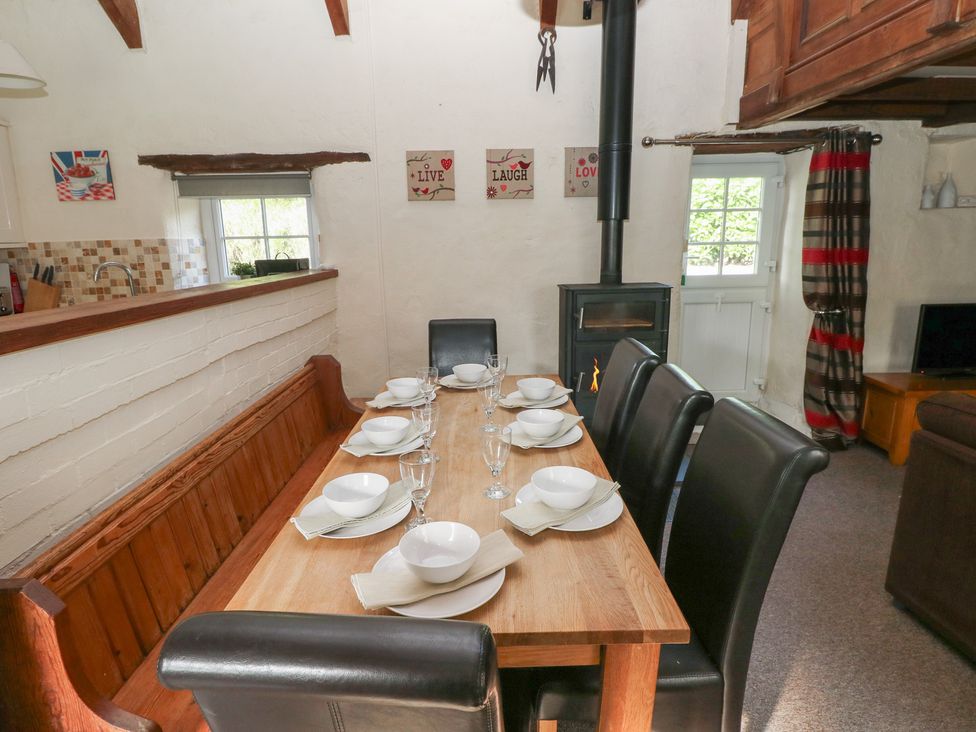 A dining room with a large table set for meals at Granary Cottage in Clarbeston Road
