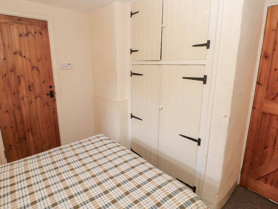 A bedroom with a bed and wardrobe at Granary Cottage in Clarbeston Road