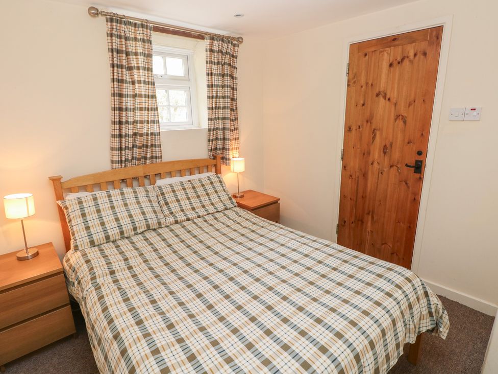A bedroom with a bed and nightstands at Granary Cottage in Clarbeston Road