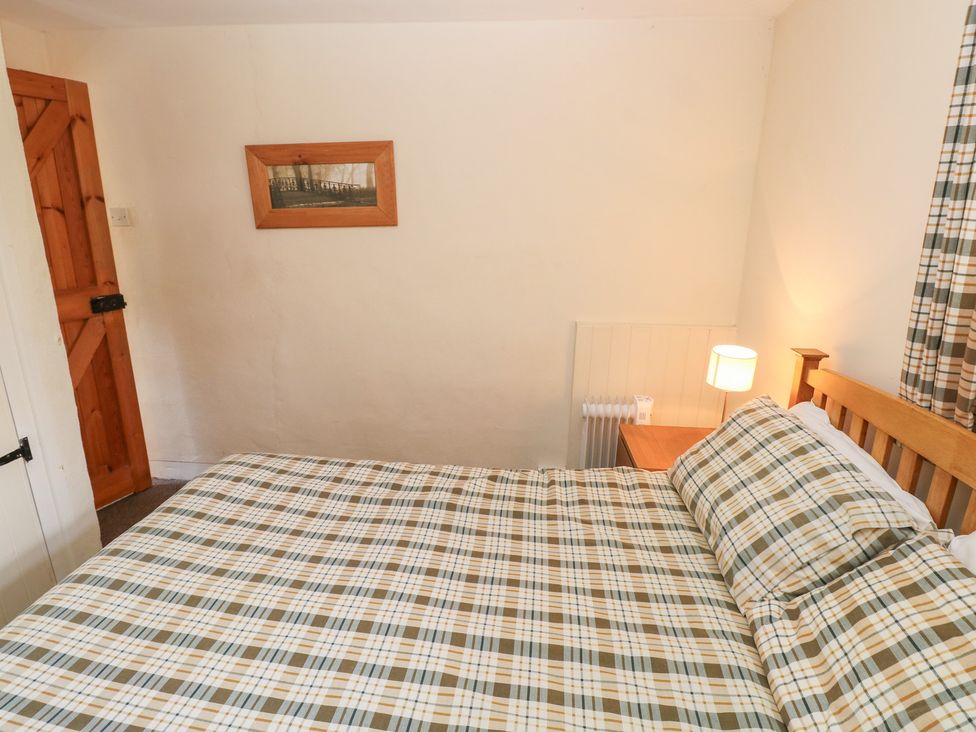 A bedroom with a bed and a lamp at Granary Cottage in Clarbeston Road