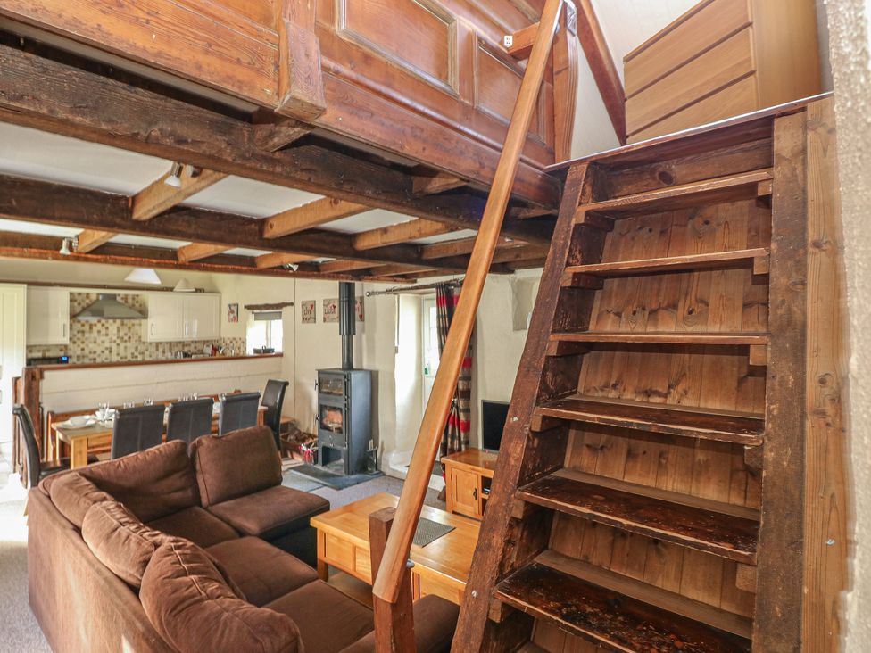 A living room with a staircase and sofa at Granary Cottage in Clarbeston Road