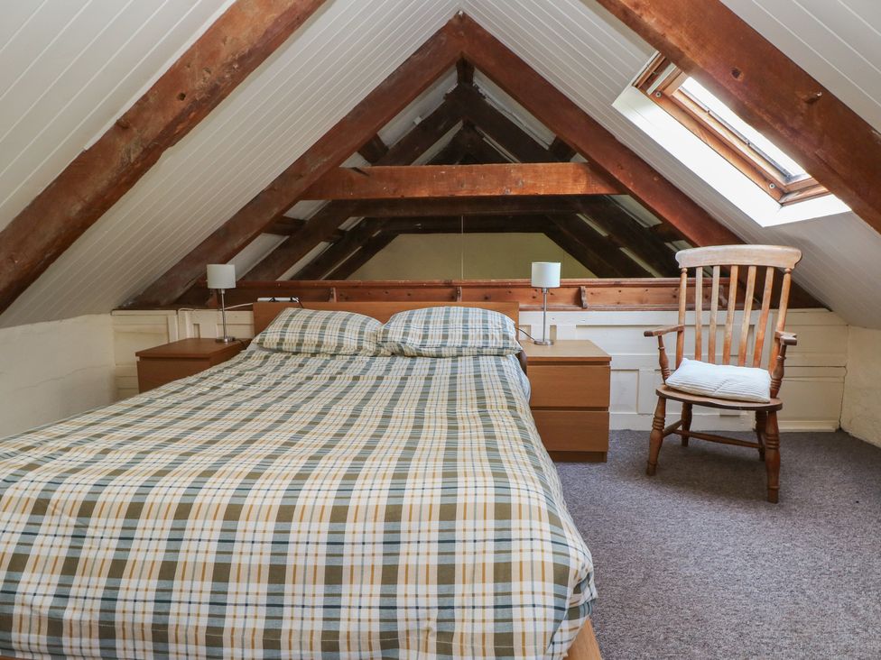 A bedroom with a bed and a chair at Granary Cottage, Clarbeston Road