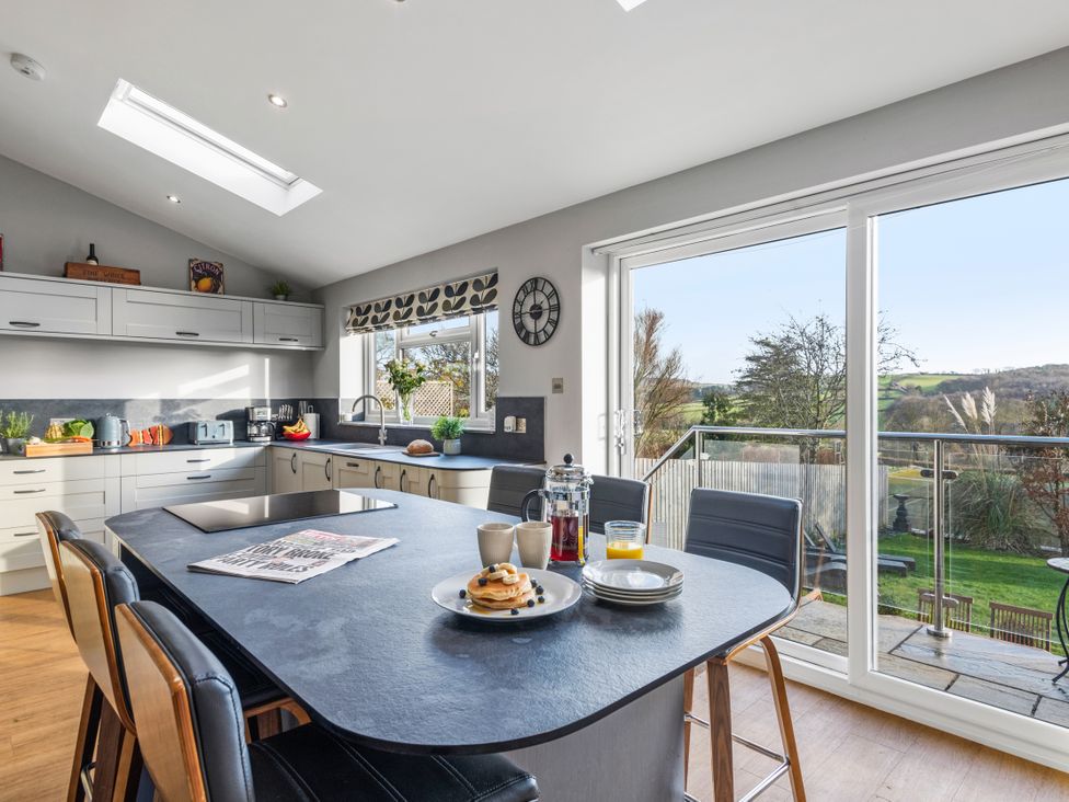 A kitchen with dining table and stools at Newlands in Yelverton