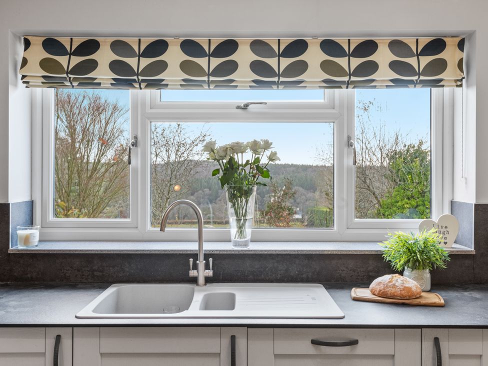 A kitchen with a sink and flowers by the window at Newlands Yelverton