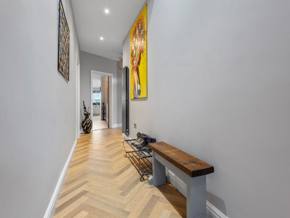 A hallway with a shoe rack and wall art at Newlands in Yelverton