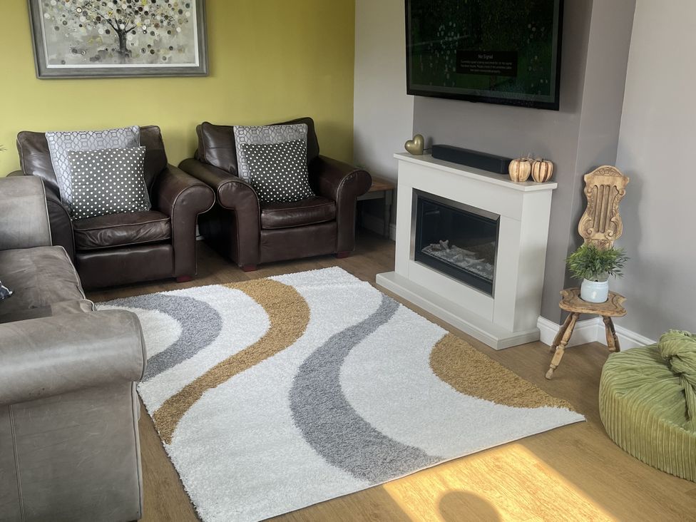 A living room with a sofa and armchairs near a fireplace at Newlands in Yelverton