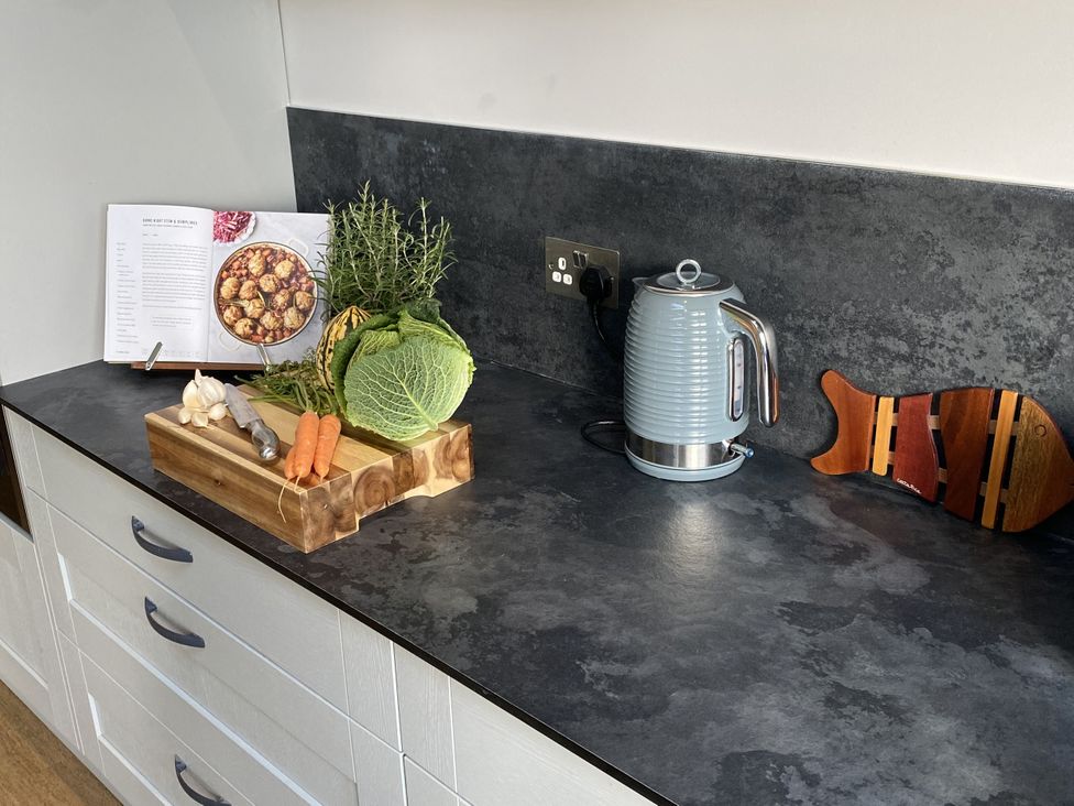 A kitchen countertop with vegetables and a kettle at Newlands in Yelverton