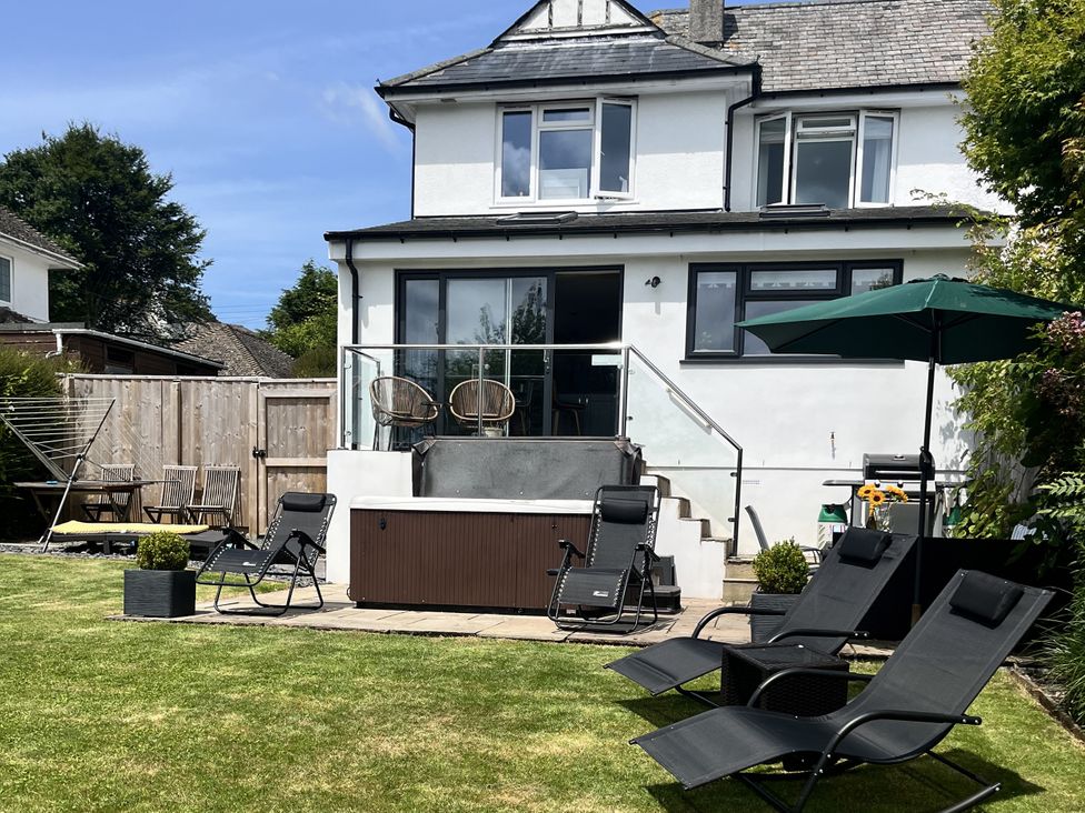 A garden with a hot tub and seating area at Newlands in Yelverton