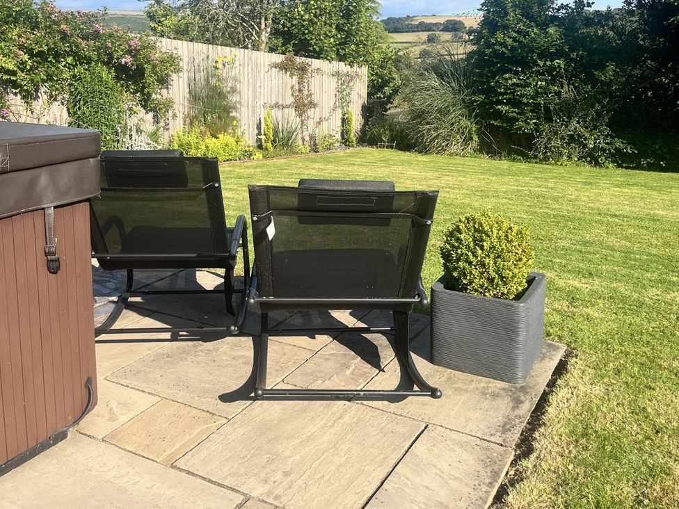 A garden with chairs and a hot tub at Newlands in Yelverton
