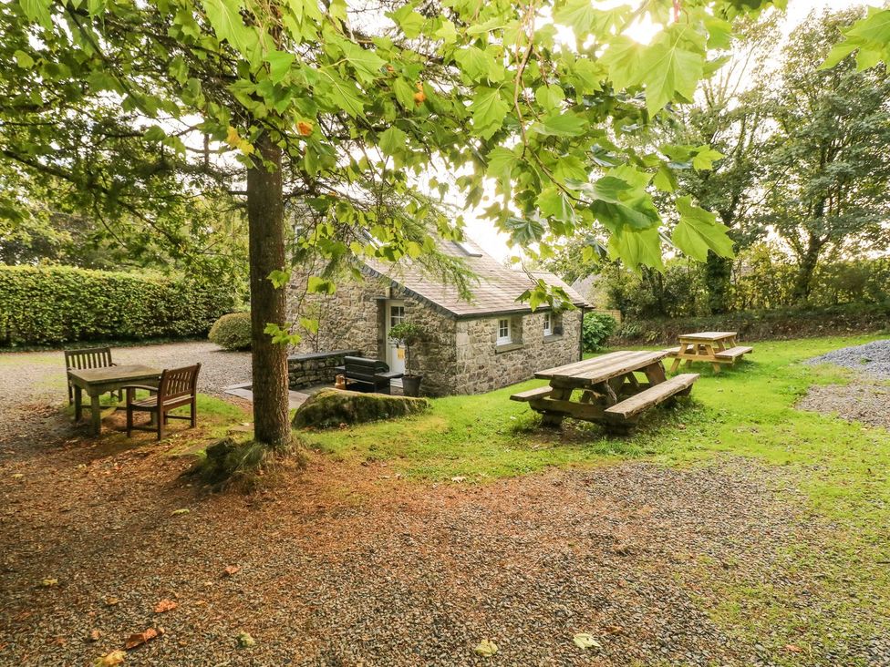 An outdoor area with a cottage, tables, and benches at Rafters Cottage in Clarbeston Road