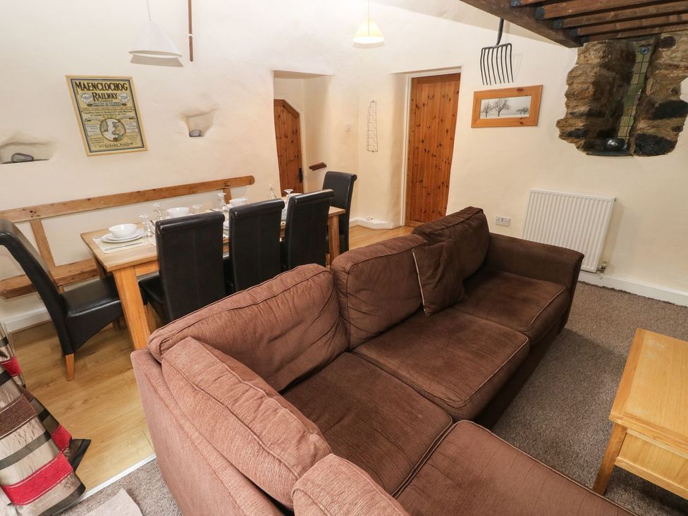 A living room with a sofa and dining table at Rafters Cottage in Clarbeston Road