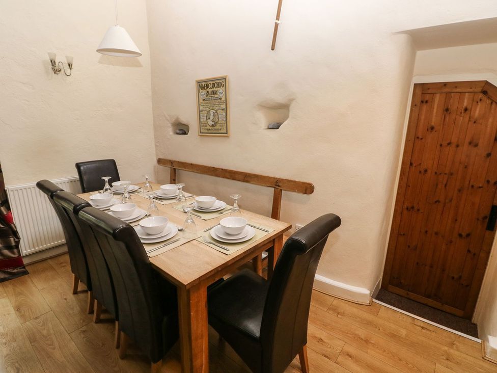 A dining room with a table set for six at Rafters Cottage in Clarbeston Road
