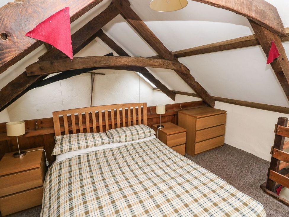 A bedroom with a bed and wooden furniture at Rafters Cottage in Clarbeston Road
