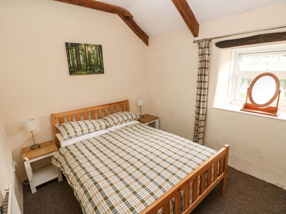 A bedroom with a bed and nightstand at Rafters Cottage in Clarbeston Road