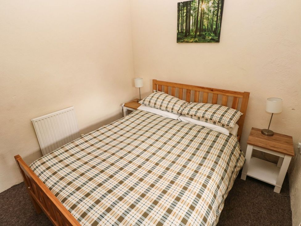 A bedroom with a bed and nightstand at Rafters Cottage in Clarbeston Road