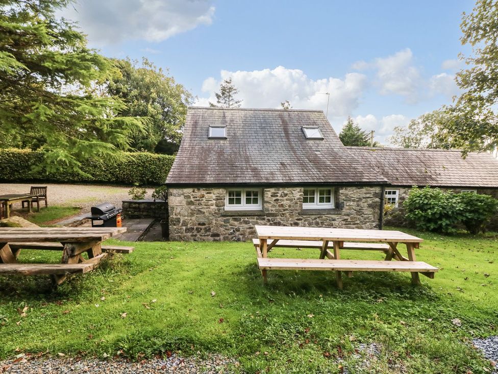 A cottage with picnic tables and a grill at Rafters Cottage in Clarbeston Road