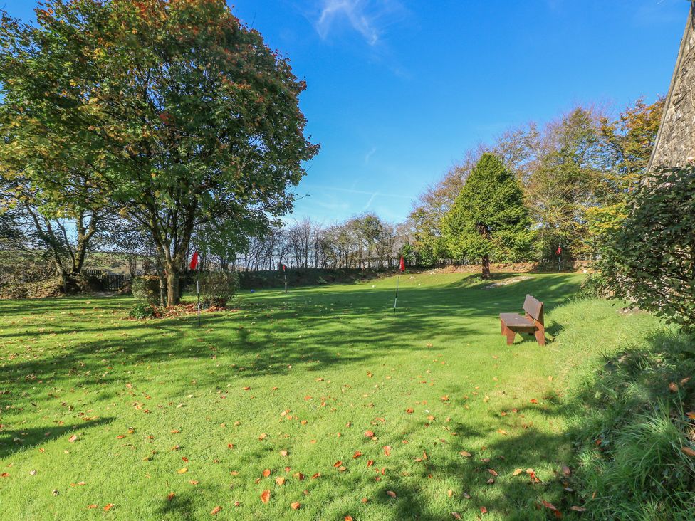 A garden with a bench and trees at Rafters Cottage in Clarbeston Road