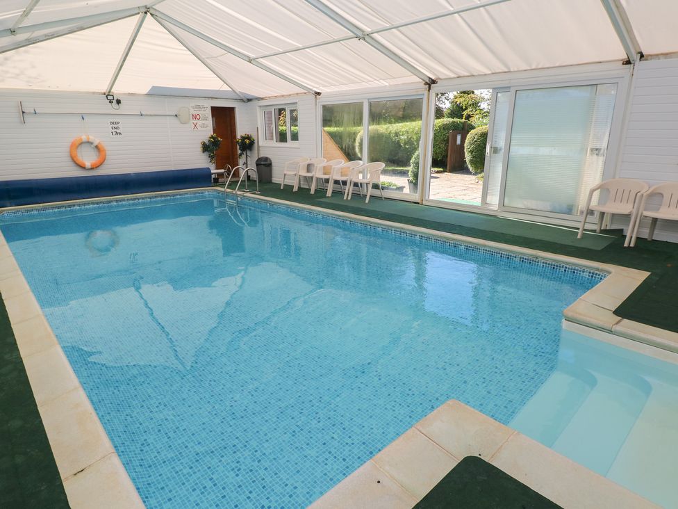 An indoor pool with sliding doors and chairs at Rafters Cottage Clarbeston Road
