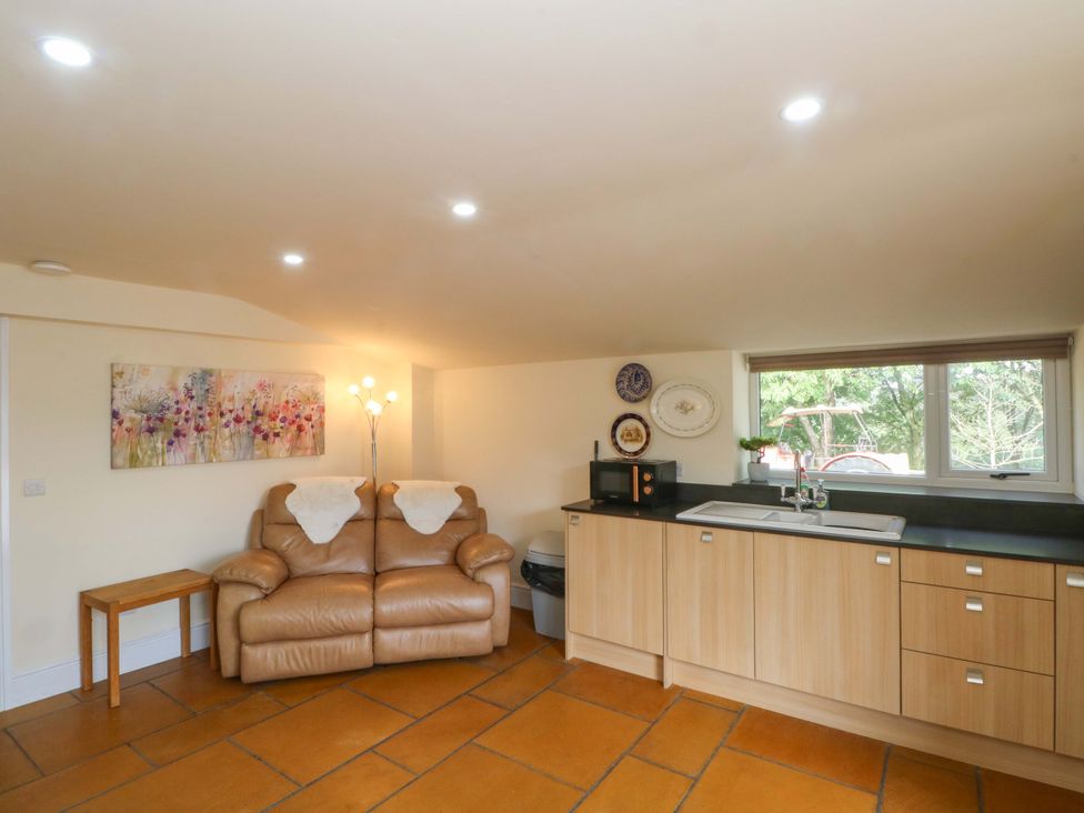 A kitchen with a sofa and microwave at The Old Shippon 